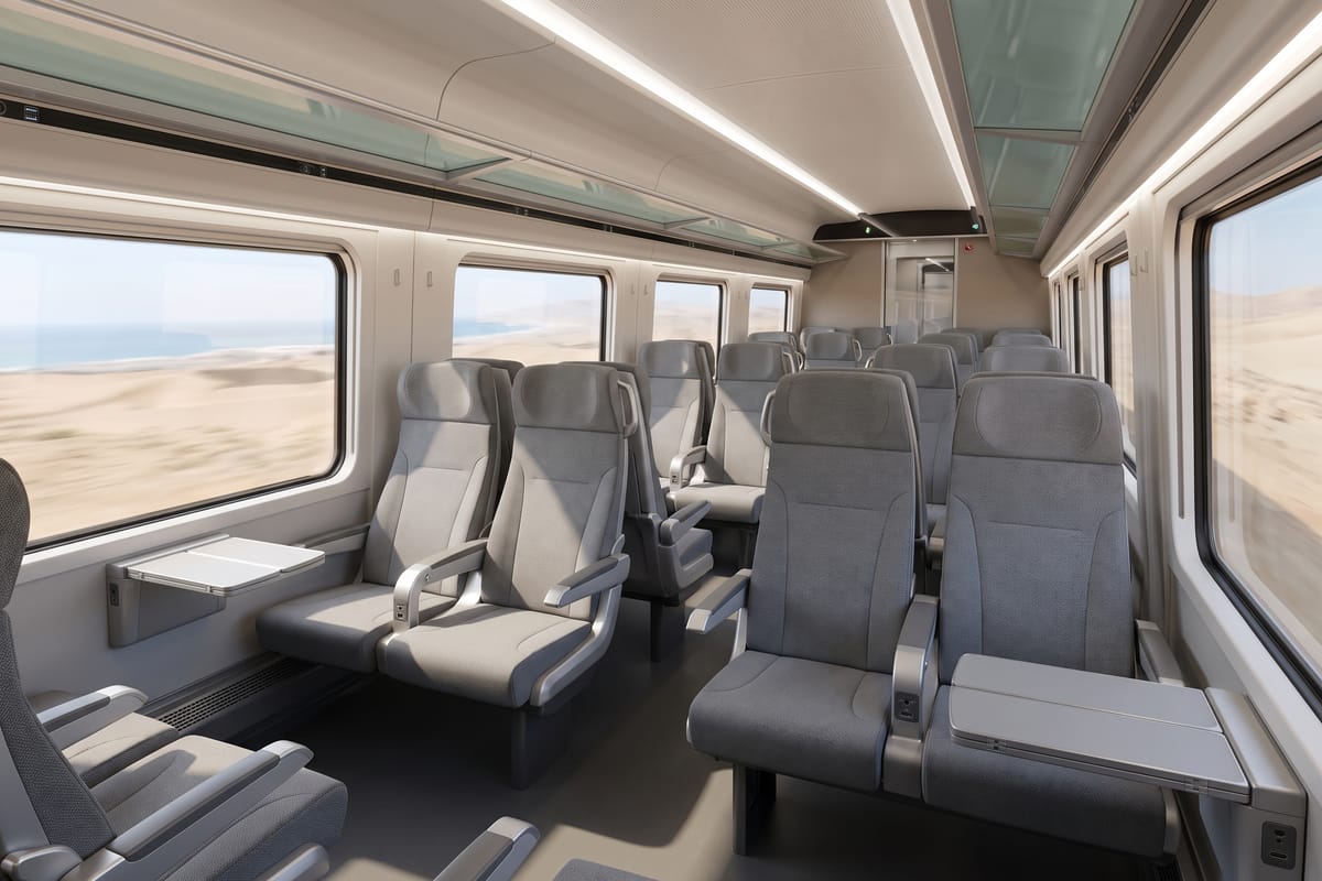 Comfort class cabin interior with grey reclining seats and fold-down tray tables, desert and coastline visible through the windows